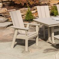 POLYWOOD® Modern Curveback Adirondack Dining Chairs arranged around an outdoor dining table set for a patio meal on stone pavers.
