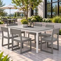 POLYWOOD® Main Street 36" x 72" Dining Table with a grey slatted tabletop and white aluminum base, surrounded by six modern dining chairs on an outdoor restaurant patio courtyard.