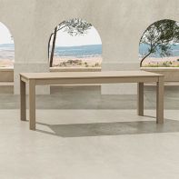 Sand-colored POLYWOOD® 84" Parsons Dining Table placed on a sunlit stone patio terrace beneath open archways overlooking an expansive scenic landscape.
